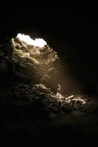 Person exploring a cave with sunlight shining through, symbolizing a journey guided by a premarital counselor Charleston.