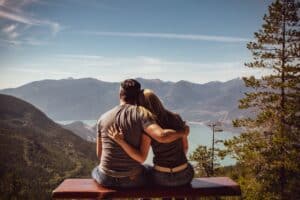 Couple sitting together on a bench overlooking mountains and a lake, symbolizing emotional connection in relationships.