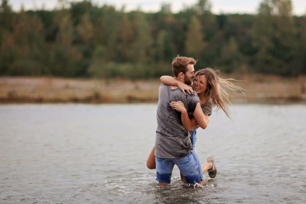 Happy couple laughing together in water representing closeness and emotional intimacy