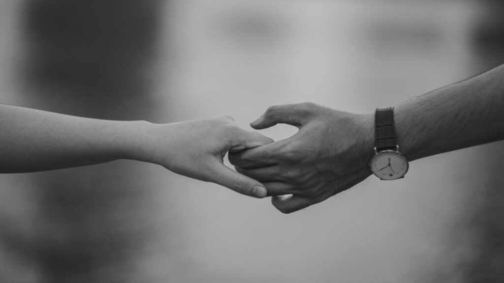 Close-up of couple holding hands, symbolizing rebuilding trust after infidelity