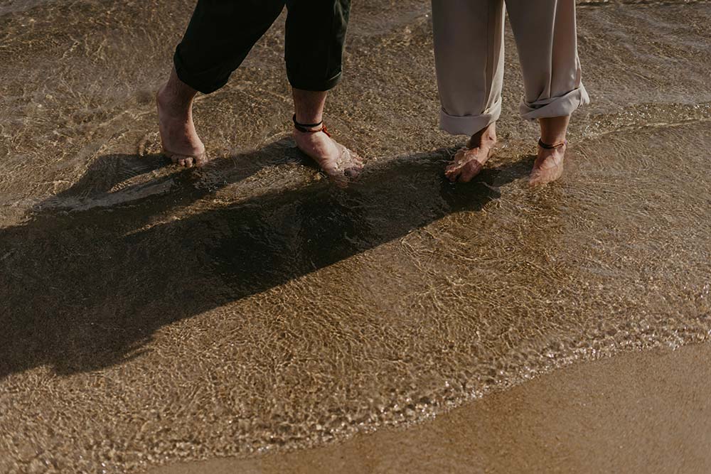 a couple of people standing on a sandy beach